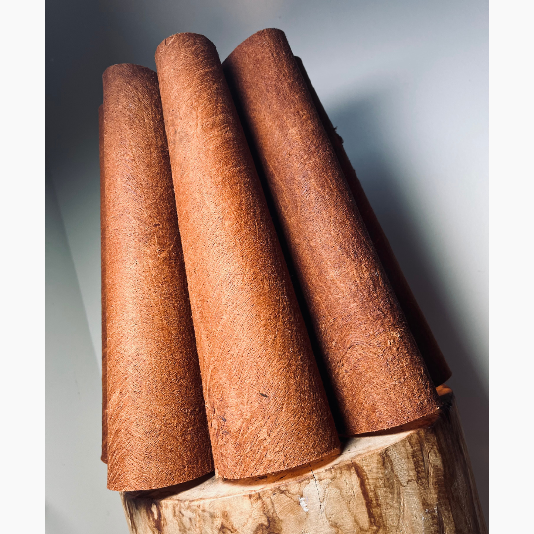 Lampe de table en forme de fleur avec des pétales en écorce d'arbre terracotta, posée sur un tabouret en bois