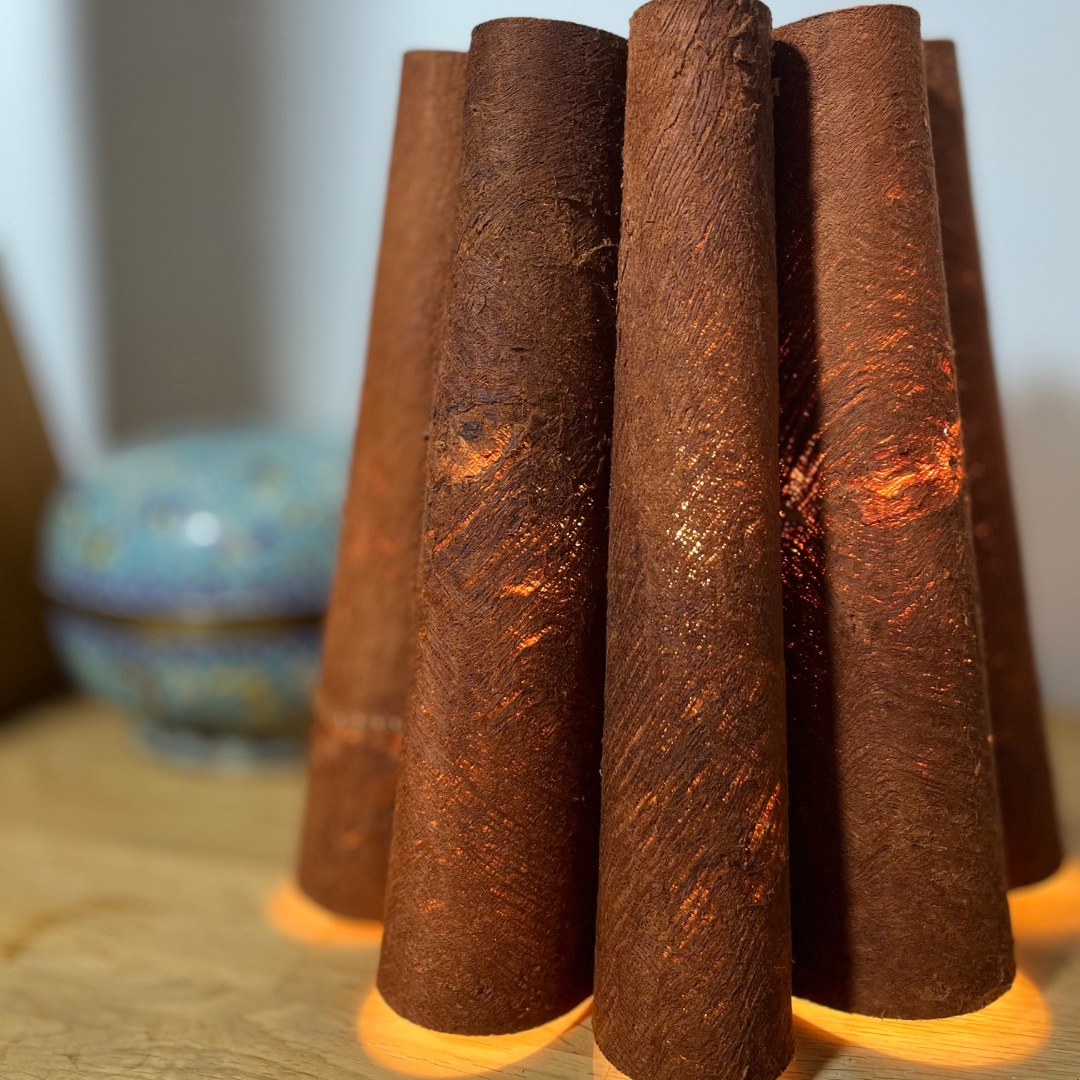 Lampe de table en forme de fleurs avec des pétales en écorce d'arbre, posée sur une table de chevet en bois