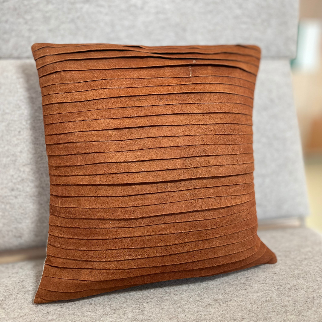 Coussin plissé en écorce d'arbre terracotta sur une assise crème, décoration d'intérieure en matière naturelle